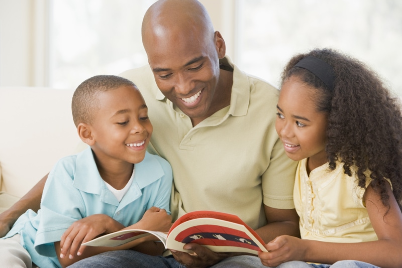father reading aloud to two children