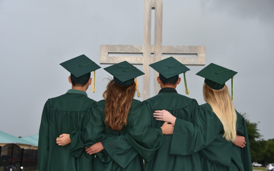 four graduates in front of a cross