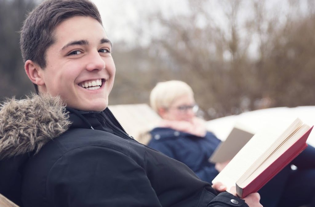 teen Boy reading outside with his mom in winter