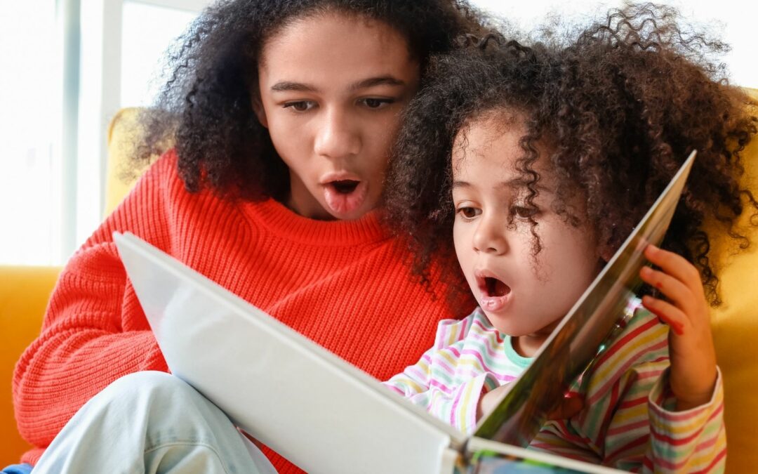 teen reading picture book to sister