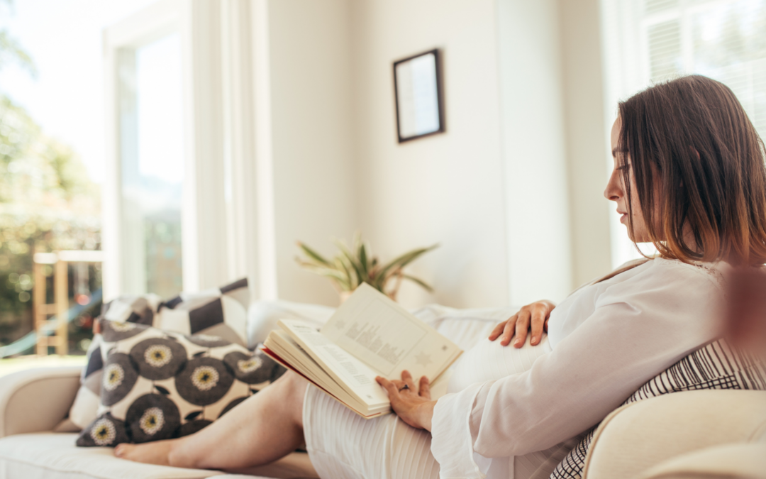 catholic homeschool mom reading on couch pregnant