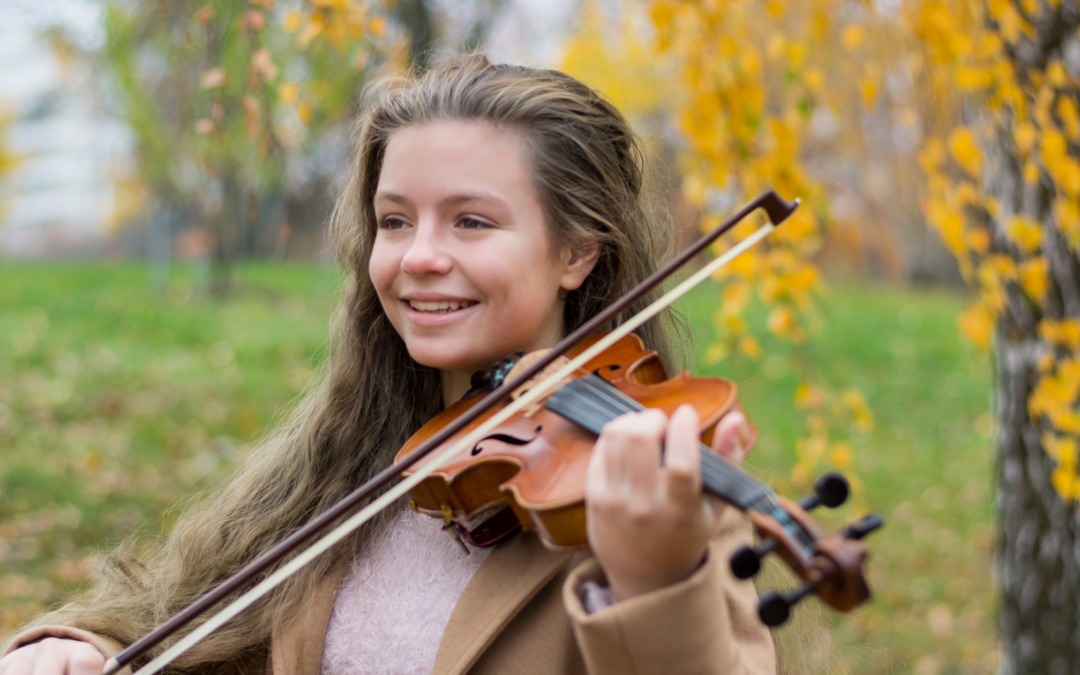 Catholic homeschool girl playing violin outdoors
