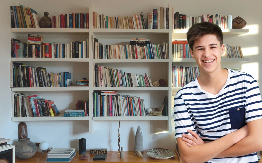 catholic homeschool teen boy standing in front of bookshelves