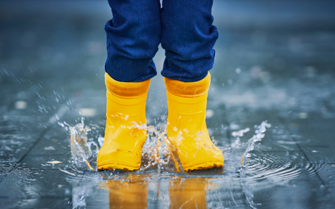 child in yellow boots splashing in pubble