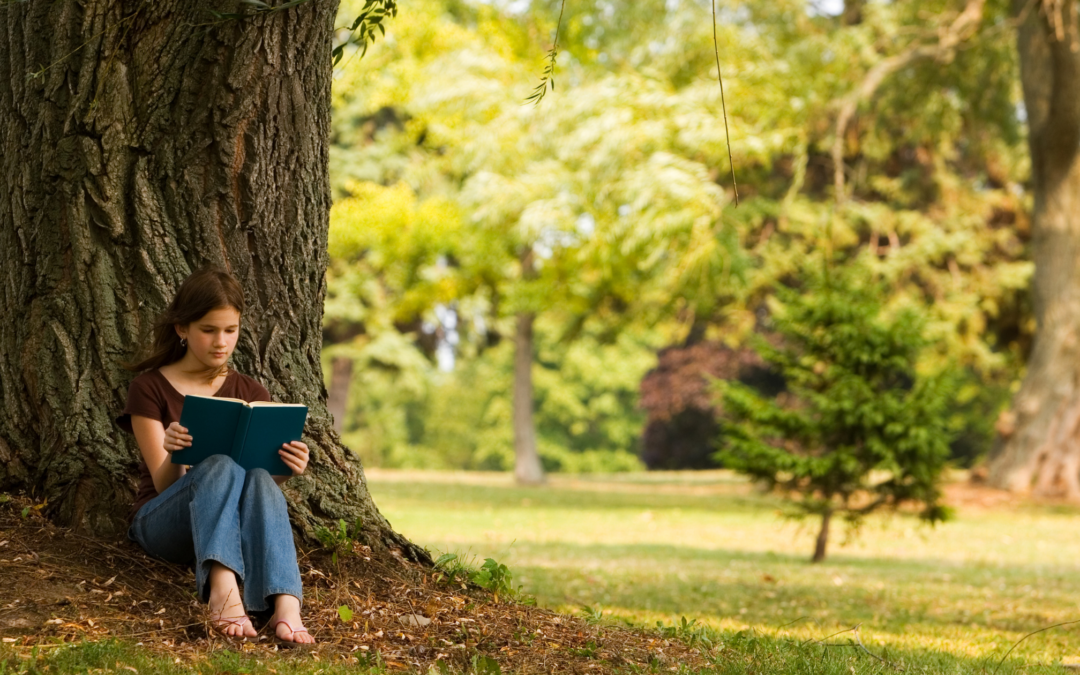 homeschool girl reading under a tree in the summer